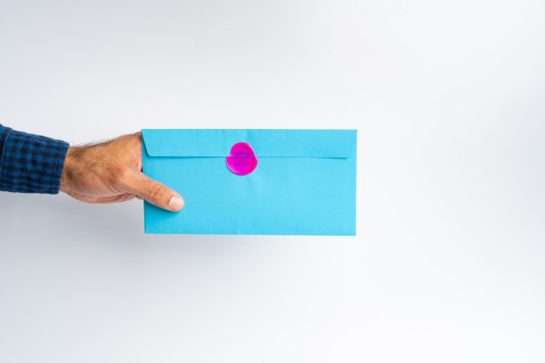 男性的手在白色表面上拿着封闭的信封图片下载