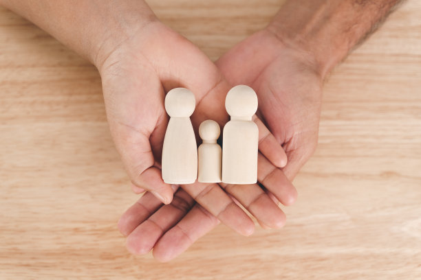 男人，丈夫和女人，妻子的手握木制钉子娃娃在木桌子的背景。家庭家庭，寄养，无家可归者慈善支持理念，家庭心理健康。图片下载