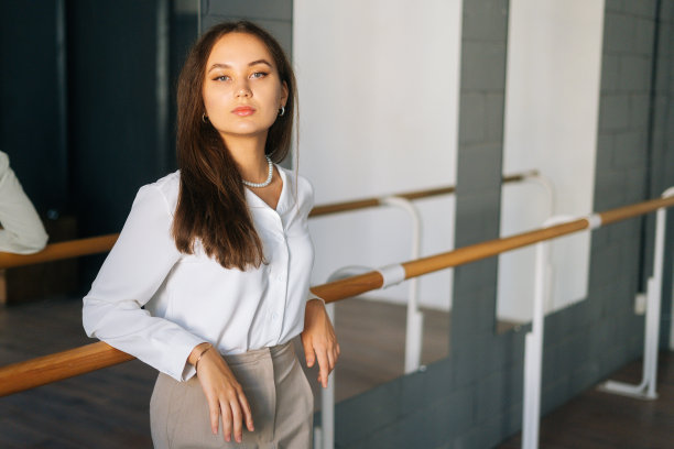 漂亮自信的年轻女人的肖像穿着时尚的衣服看着镜头站在镜子的房间。图片下载