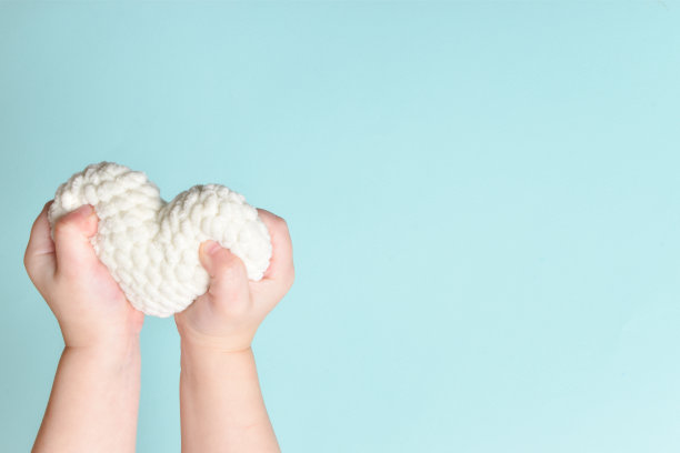 孩子们的手握着一颗蓝色背景的白色小心形。爱。图片下载