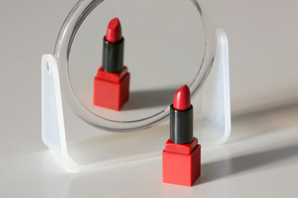 单管开缎面红色唇膏和化妆镜放在桌子上，工作室拍摄图片下载