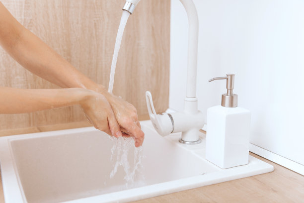 在水龙头下洗手。用肥皂洗手以预防冠状病毒的传播，防止冠状病毒在公共卫生间或公共卫生间的卫生传播。卫生概念手部细节图片下载