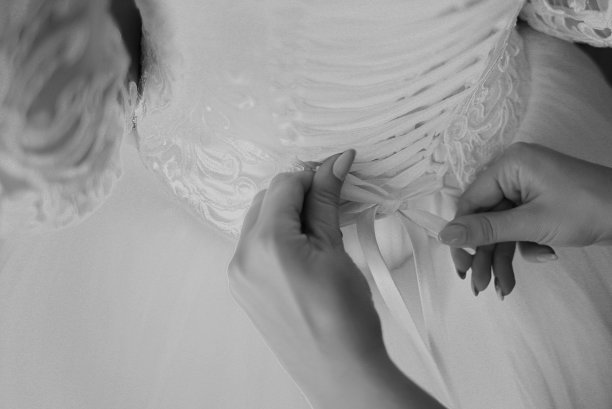 时装设计师正在修改婚纱。早上准备。女人穿上裙子。图片下载