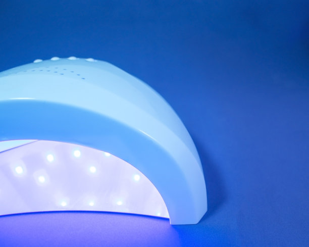 紫外线钉灯。特殊紫外线灯与紫外线的各种用途。在美容院的紫外线灯下修指甲。图片下载