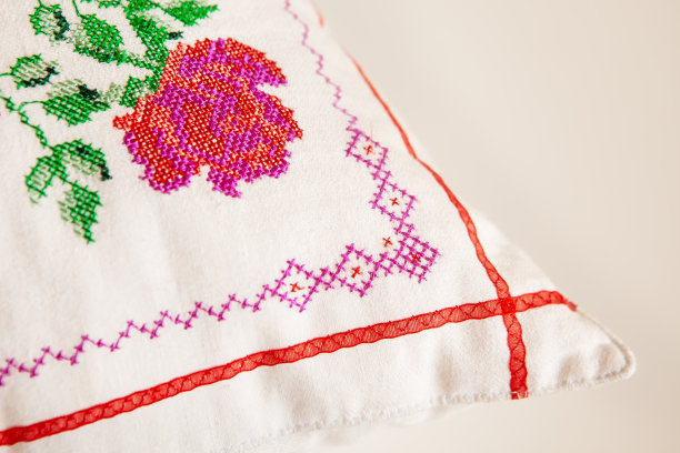 装饰元素，十字绣玫瑰花，在白色亚麻布织物上。绣花机,特写。图片下载