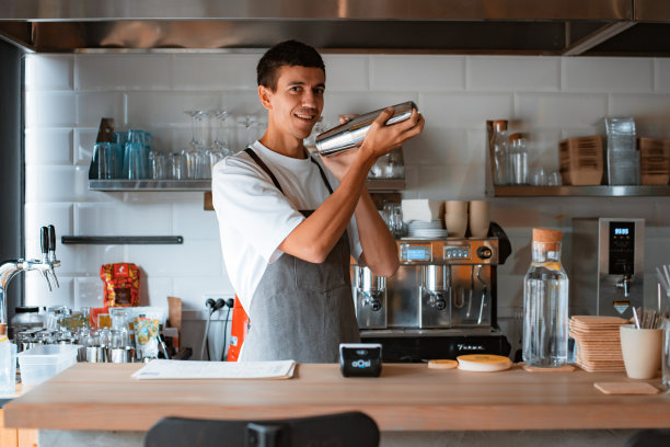 微笑的专业男咖啡师制作焦糖冰咖啡，同时在当地的咖啡店工作图片下载