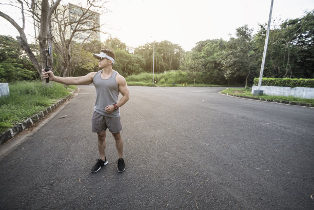 一个健康的亚洲男人在他的视频博客边走在空荡荡的路上在清晨。图片下载