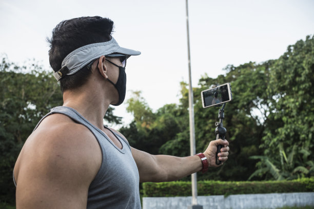 一个戴着口罩的健康男子做了一个关于户外慢跑的健身视频博客。社交媒体与锻炼理念。图片下载