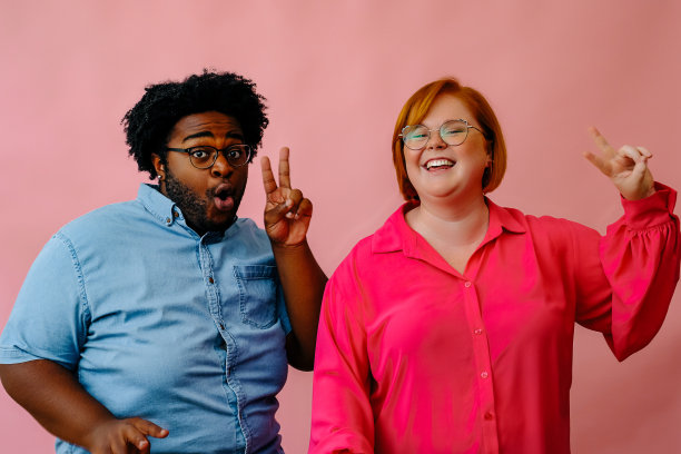 快乐的朋友们在粉色背景的工作室里一起摆姿势图片下载