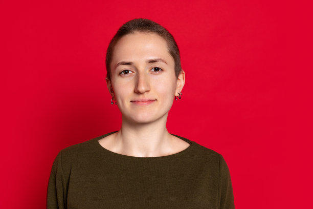 年轻微笑的女人的肖像，学生短头发在黑色毛衣孤立在红色的背景。情感概念，学习，广告图片下载