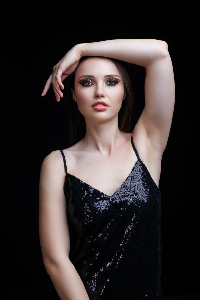 漂亮的年轻女子穿着黑色的连衣裙，脸上带着闪亮的妆容。图片下载