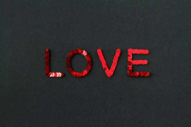 题词“爱”绣红色亮片在黑色纹理背景图片下载