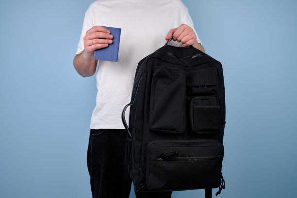 一名男子手里拿着一本护照和一个旅行袋，背景是蓝色的。时间旅行图片下载
