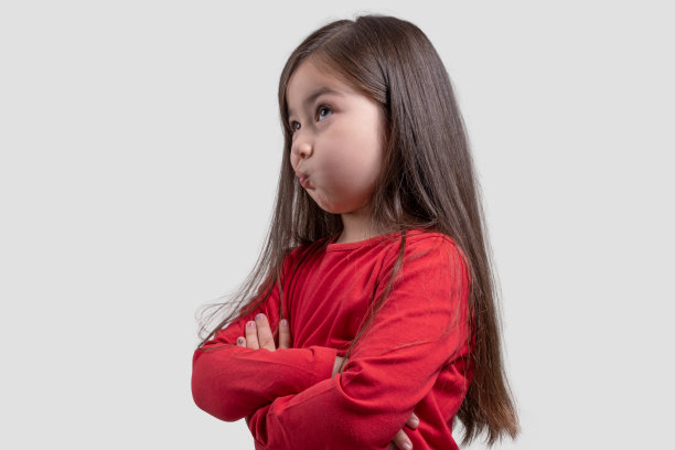 一个思考的小女孩的肖像，在灰色的背景上看着沉思的面部表情图片下载