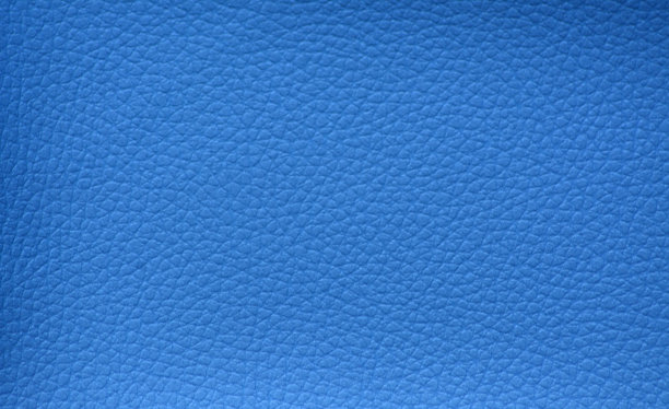 带有小网格图案的天然皮革碎片，并在明亮的蓝色特写中人工染色。图片下载