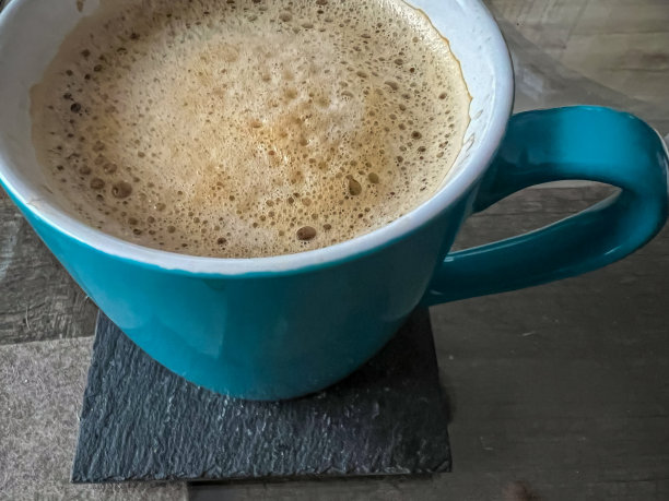 一杯刚煮好的咖啡放在玻璃桌上的杯垫上。图片下载