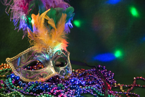LV狂欢节上的亮片面具，用羽毛装饰在铺有羽毛的床上。彩色的珠子和聚光灯的颜色。图片下载