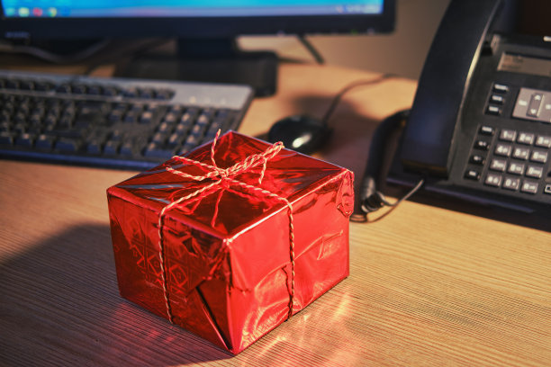 在圣诞节和新年前夕，办公室的桌子上有一个礼品盒。节日的惊喜和礼物图片下载