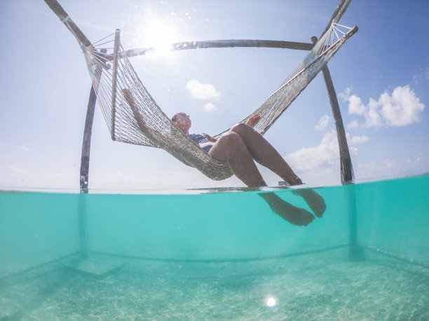 一名女子在热带泻湖上的吊床上放松，水下有屏风图片下载