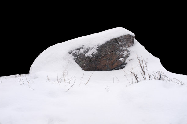 自然的石头在雪孤立在黑色的背景上图片下载