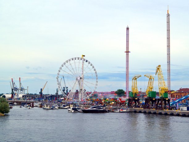 图中是一个拥有风格化港口起重机的游乐园。游艇、船、船都停泊在岸边。图片下载