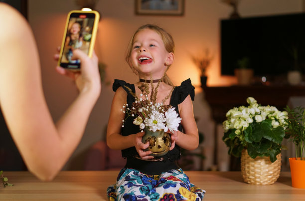 用万圣节南瓜在手机上做一个照片小孩。网上直播或网上呼吁放假。一个女人正在给她的女儿拍照。用手机拍张照片。家庭雕刻南瓜图片下载