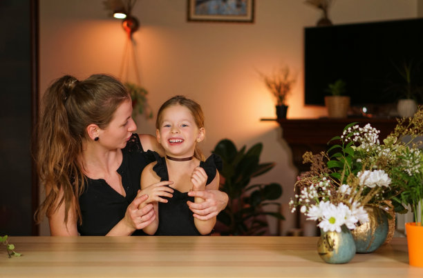 万圣节快乐。两个女孩和一个南瓜在桌子上。明亮的背景与橙色照明。节日的欢乐。拥抱和笑。两姐妹和带着女儿的妈妈在家里很开心图片下载