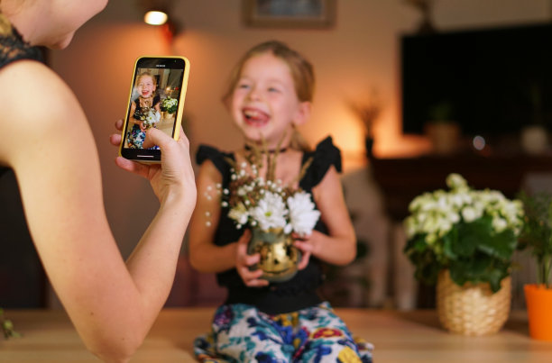 用万圣节南瓜在手机上做一个照片小孩。网上直播或网上呼吁放假。一个女人正在给她的女儿拍照。用手机拍张照片。家庭雕刻南瓜图片下载