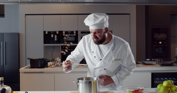 穿着制服的厨师在尝锅里的恶心酱汁图片下载