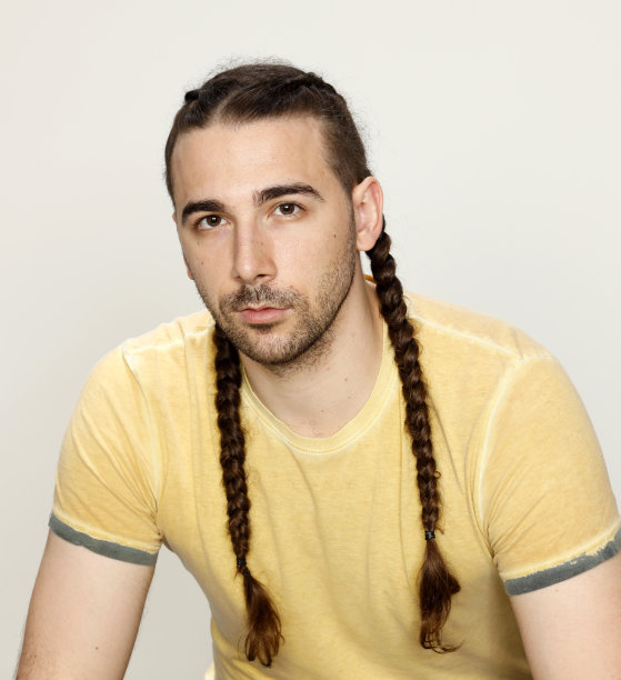 时尚的男性模型与辫子摆姿势在工作室孤立的背景。图片下载