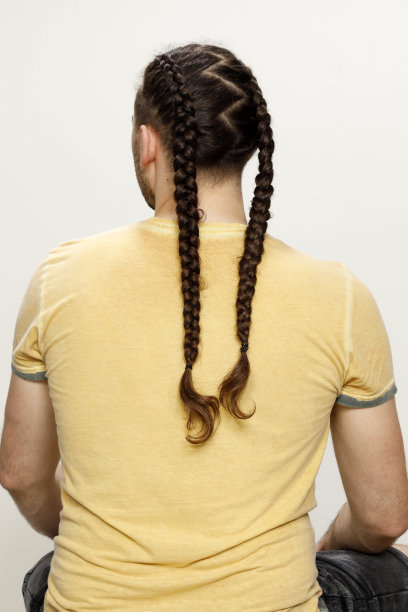 时尚的男性模型与辫子摆姿势在工作室孤立的背景。图片下载