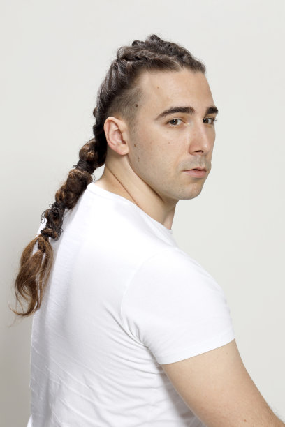 时尚的男性模型与辫子摆姿势在工作室孤立的背景。图片下载
