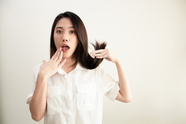 亚洲美丽的女人用手触摸嘴唇和持有她的头发担心和震惊的脸关于头发分裂和干燥的问题图片下载