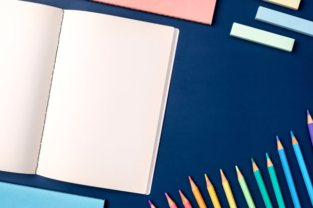 俯视图蜡笔笔记本与铅笔和文具在海军蓝的桌子背景图片下载