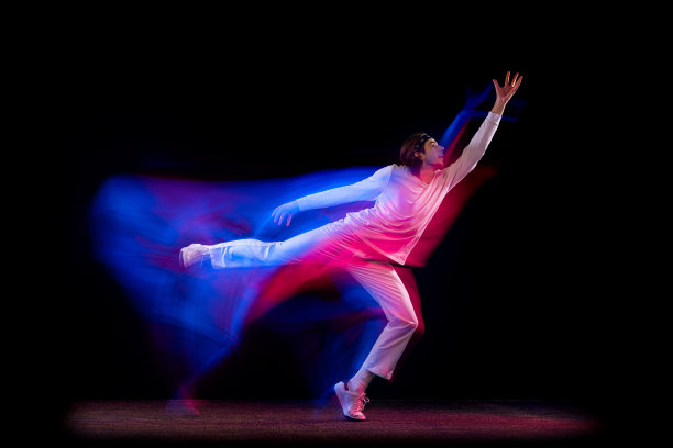 动态肖像男性嘻哈舞者孤立在黑暗的背景下混合霓虹灯跳舞。青年文化，嘻哈，运动，时尚，时尚，行动。图片下载