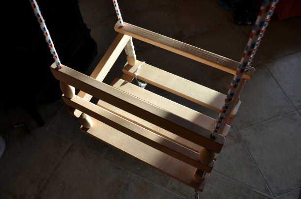 客厅的横梁上挂着一个儿童秋千，从天花板上垂下来。阳光照进小屋的房间。生产和销售不含塑化剂和油漆的天然木材制成的儿童玩具和艾滋病图片下载