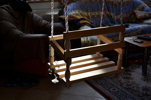 客厅的横梁上挂着一个儿童秋千，从天花板上垂下来。阳光照进小屋的房间。生产和销售不含塑化剂和油漆的天然木材制成的儿童玩具和艾滋病图片下载