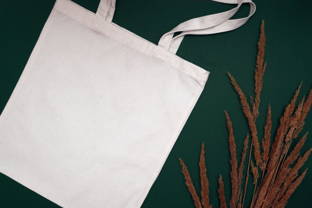 模拟环保米色或白色帆布棉织物手提袋上深绿色的背景。购物袋模型空白模板。可重复使用的杂货和购物袋。图片下载