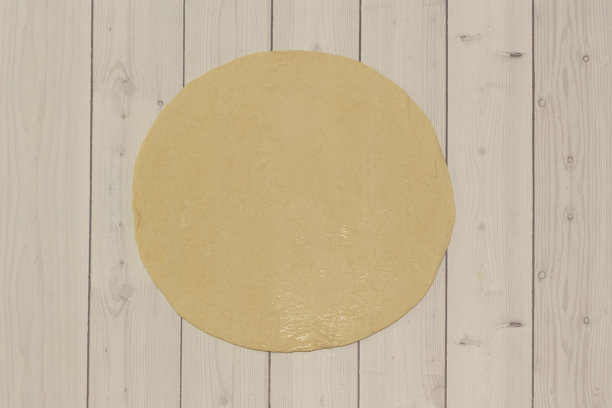 木制桌子上的圆形披萨面团。图片下载