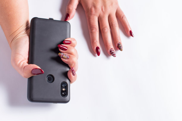 女性手持电话。手与指甲握电话在白色背景。图片下载