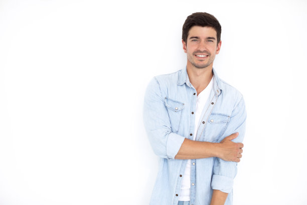 年轻英俊的男子面带笑容，穿着牛仔衬衫，白色的背景。图片下载
