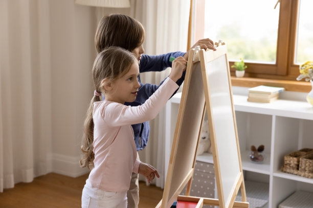 两个可爱的兄弟姐妹在玩具小白板上画画图片下载