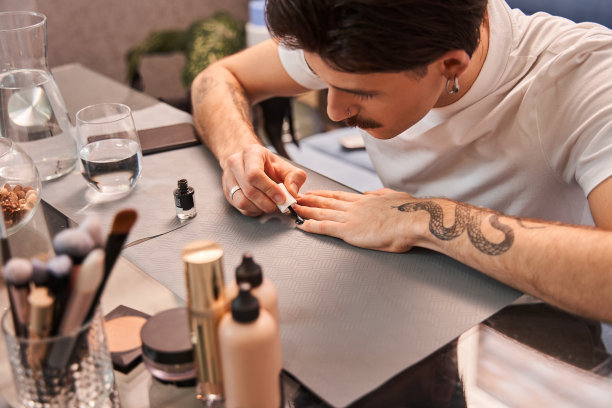 漂亮的帅哥坐在家里做时尚的美甲图片下载