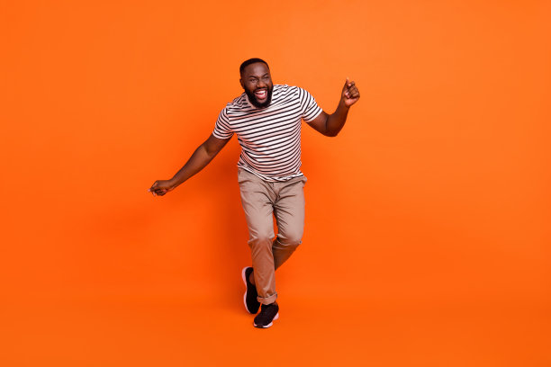 全尺寸照片青年兴奋的非洲人有乐趣舞者事件俱乐部孤立在橙色背景图片下载