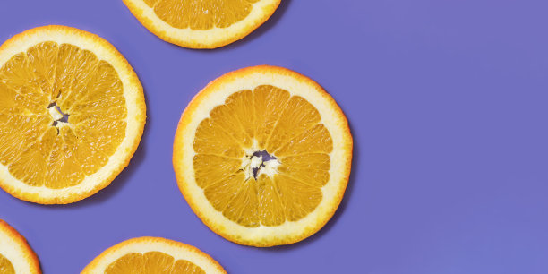 切成薄片的水果橙子在紫罗兰色的背景上的格子图案。水果背景从一片橙子。展示了非常艳丽、2022年的色彩。图片下载