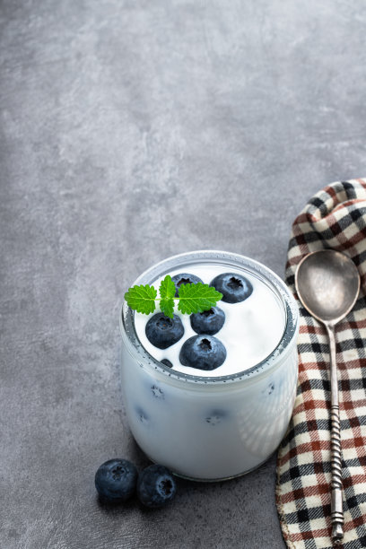 白色的奶油酸奶和新鲜的蓝莓小罐放在灰色的桌子上图片下载