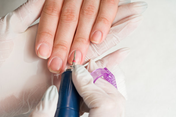 一位妇女在美甲沙龙接受美容师用指甲锉修指甲。美容和手部护理特写图片下载