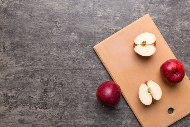 桌上有新鲜的红苹果和绿叶。用刀切菜板。俯视图图片下载