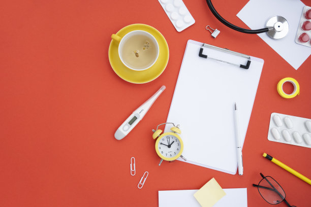顶部视图的医生的桌面在红色背景与复制空间。用于笔记的药片，听诊器，眼镜，药丸，药物，一杯花草茶，手表。平坦的躺,模型图片下载