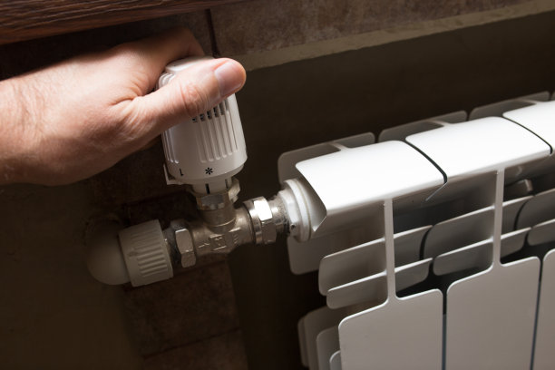 一个男人的手在检查白色暖气片上的暖气图片下载